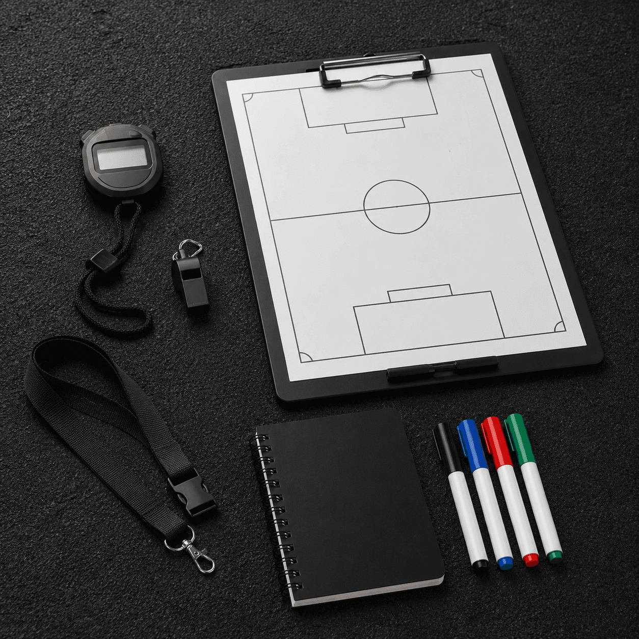 Coach timer, whistle, tactical board, and notebook on a training surface